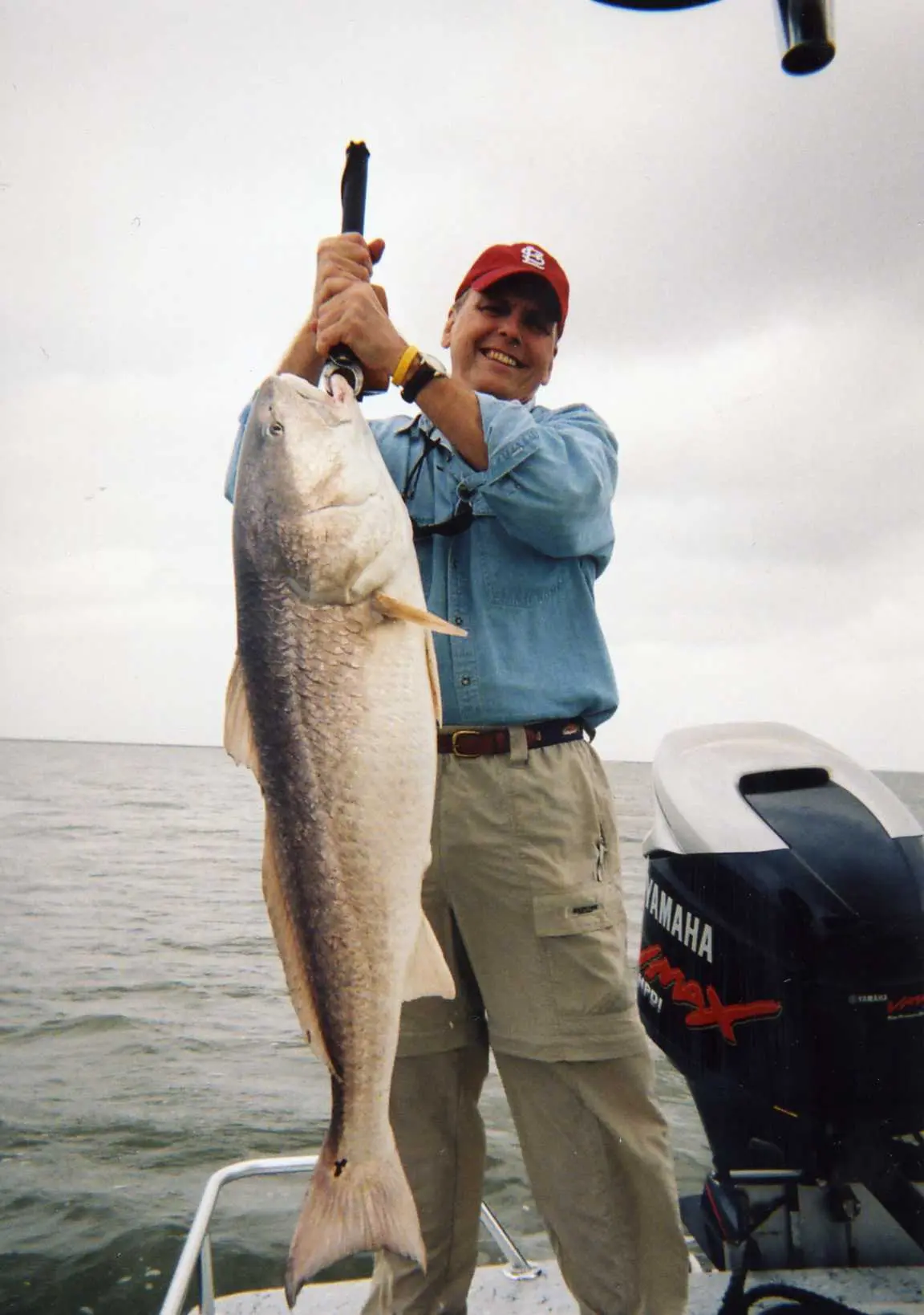 Angler holding a large inshore catch aboard a boat.