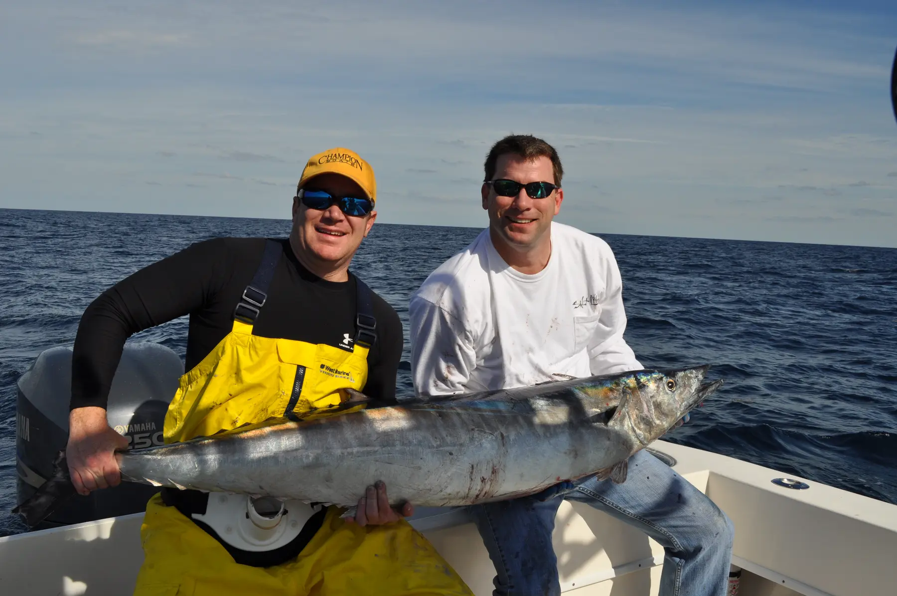 Two anglers holding a large wahoo offshore.