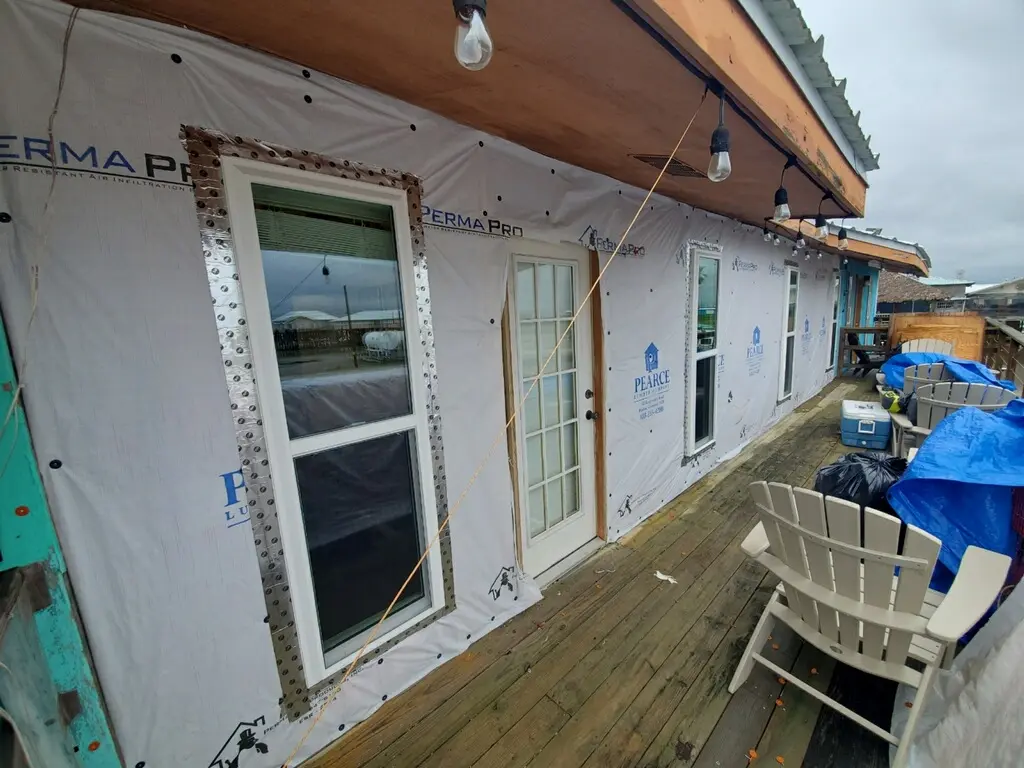 The exterior of The Alibi covered in house wrap with newly installed windows and metal flashing.