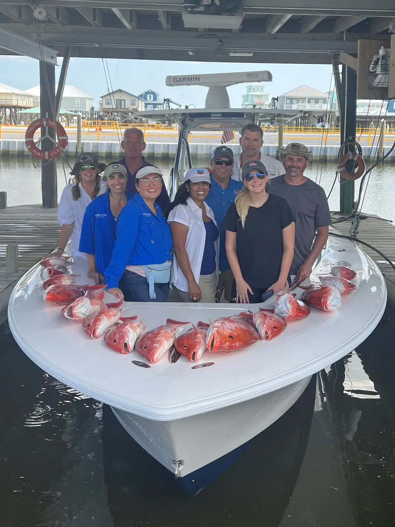 Nine guests with a red snapper catch beside the Miss Trial at the dock.